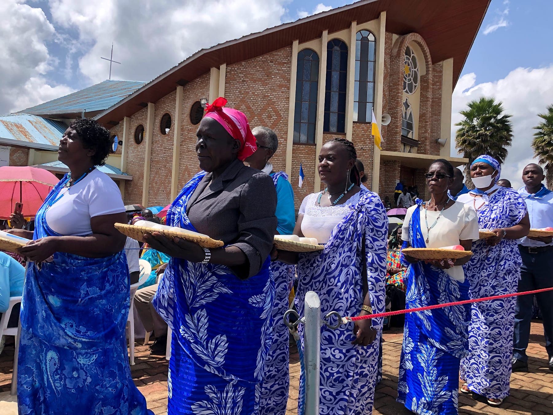 Women in blue carrying offerings in procession at the Kibeho shrine